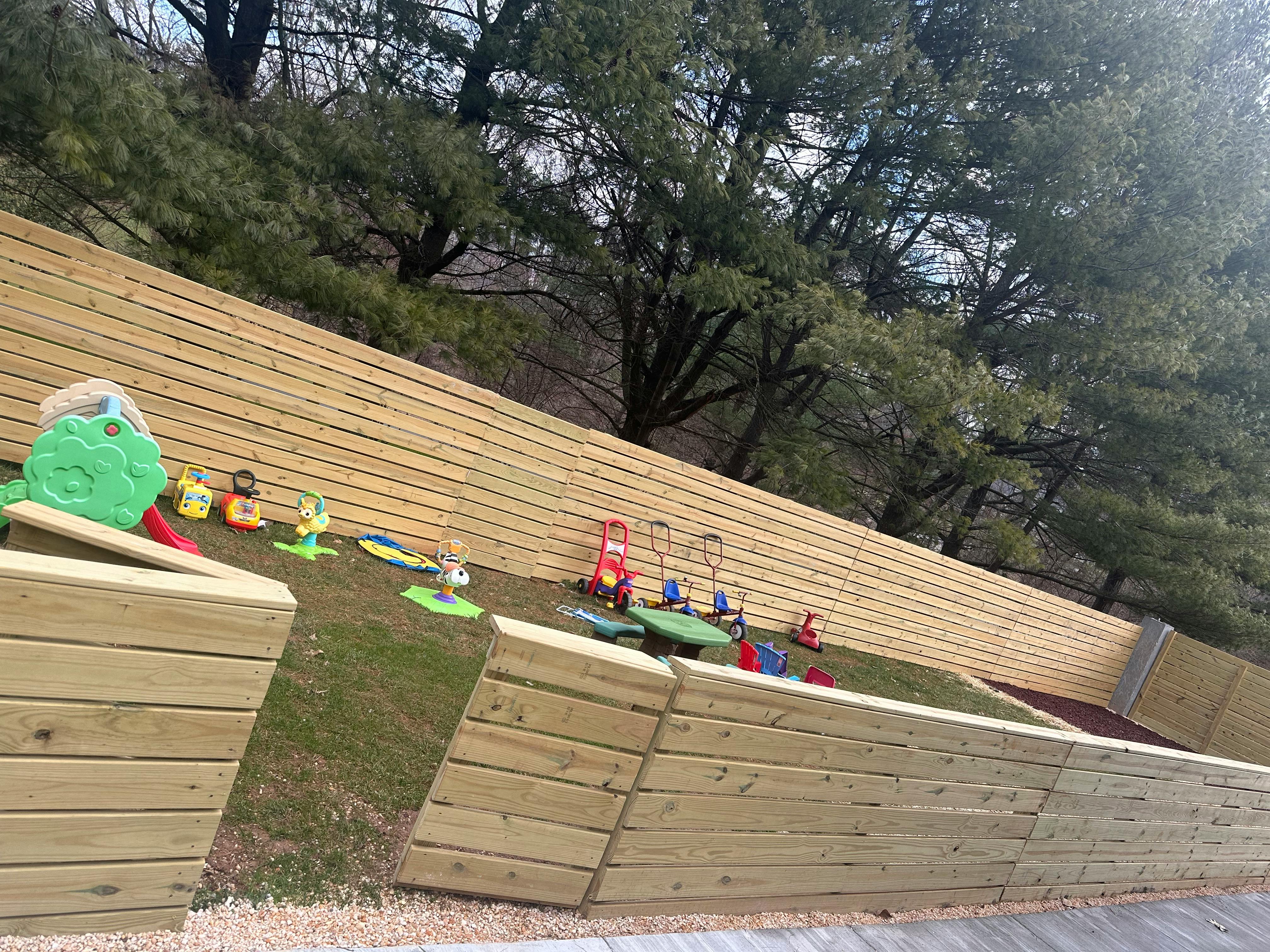 Playground with wooden retaining walls and various toys on grass