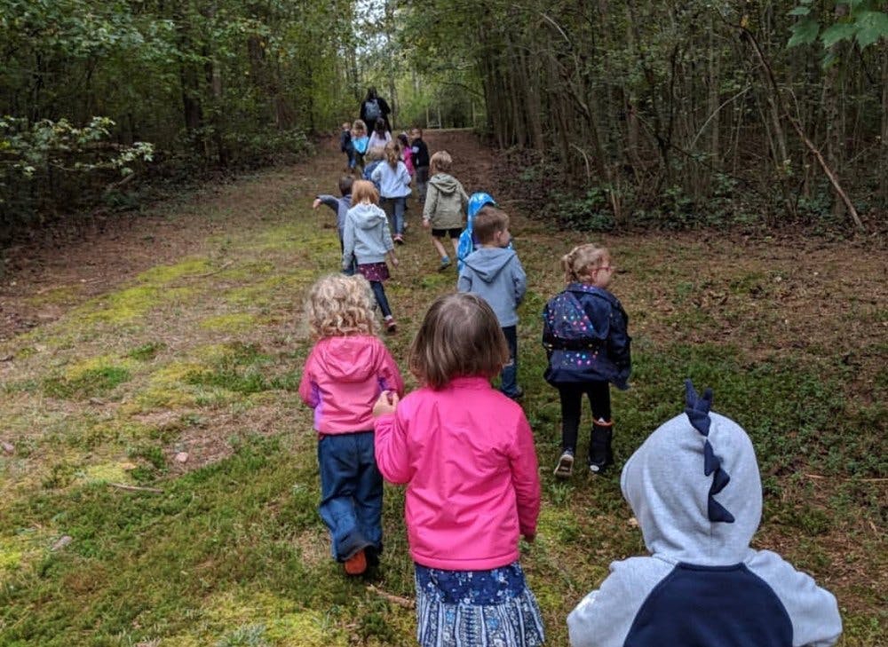 Group of children walking on a path through a wooded area