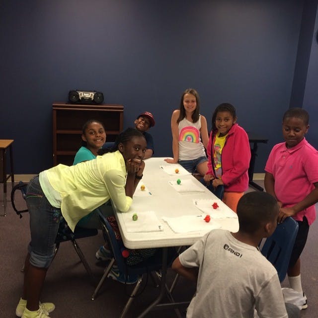 Group of children gathered around a table with small objects