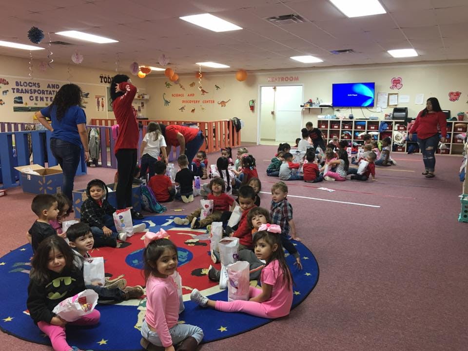 Adults and children gathered in a large room, some sitting on the floor