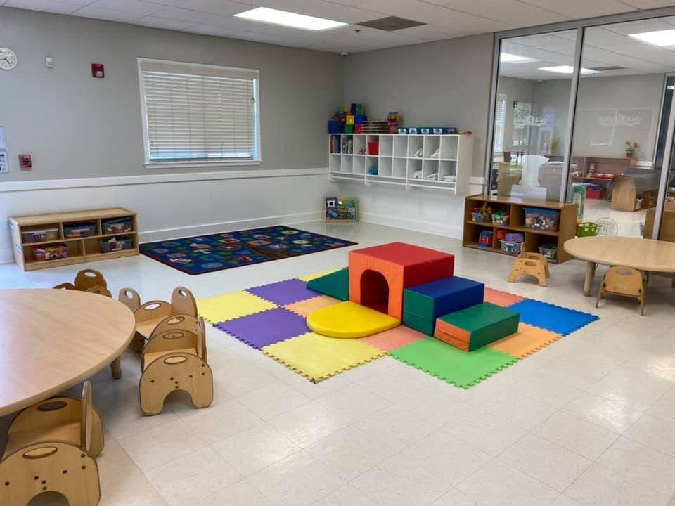 Playroom with colorful soft play equipment, tables, and chairs