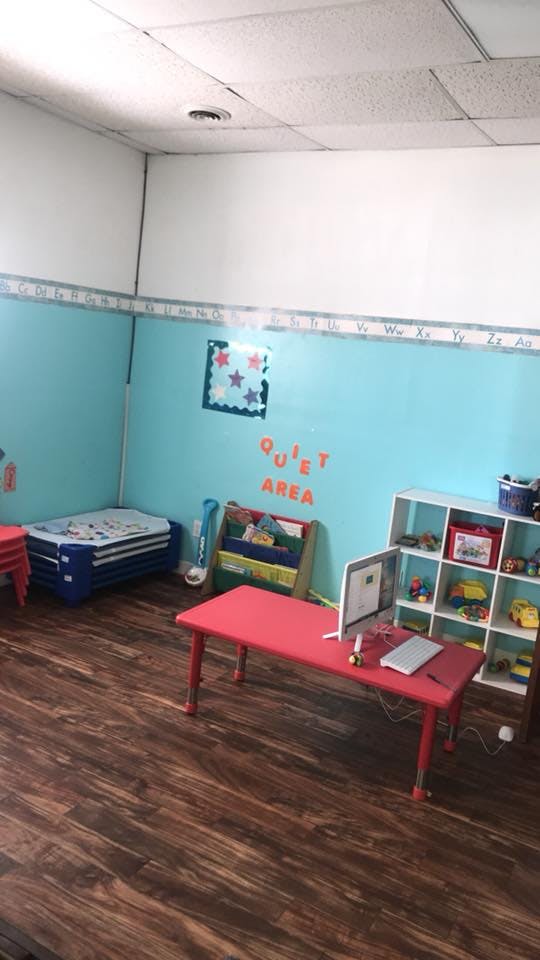 Classroom with red tables, toy shelves, and a quiet area sign