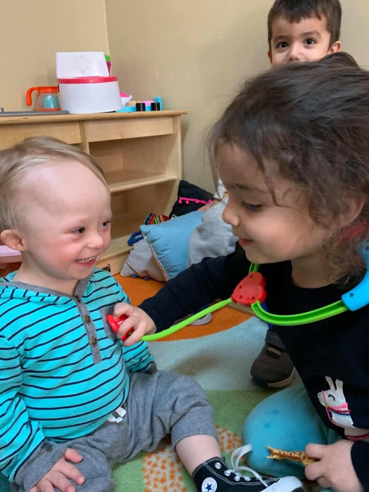 Child playing doctor with another child using a toy stethoscope