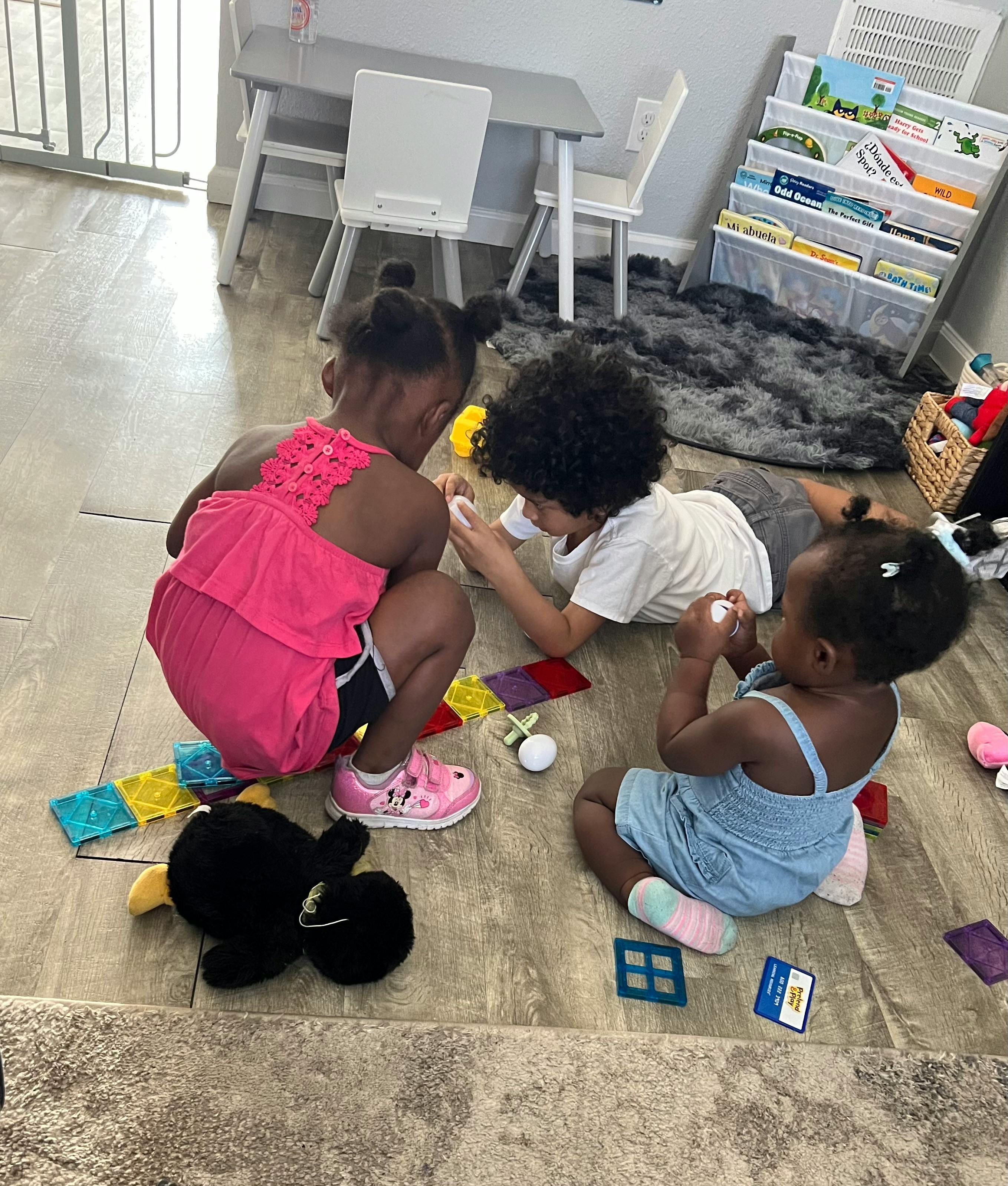 Three children playing on the floor with toys