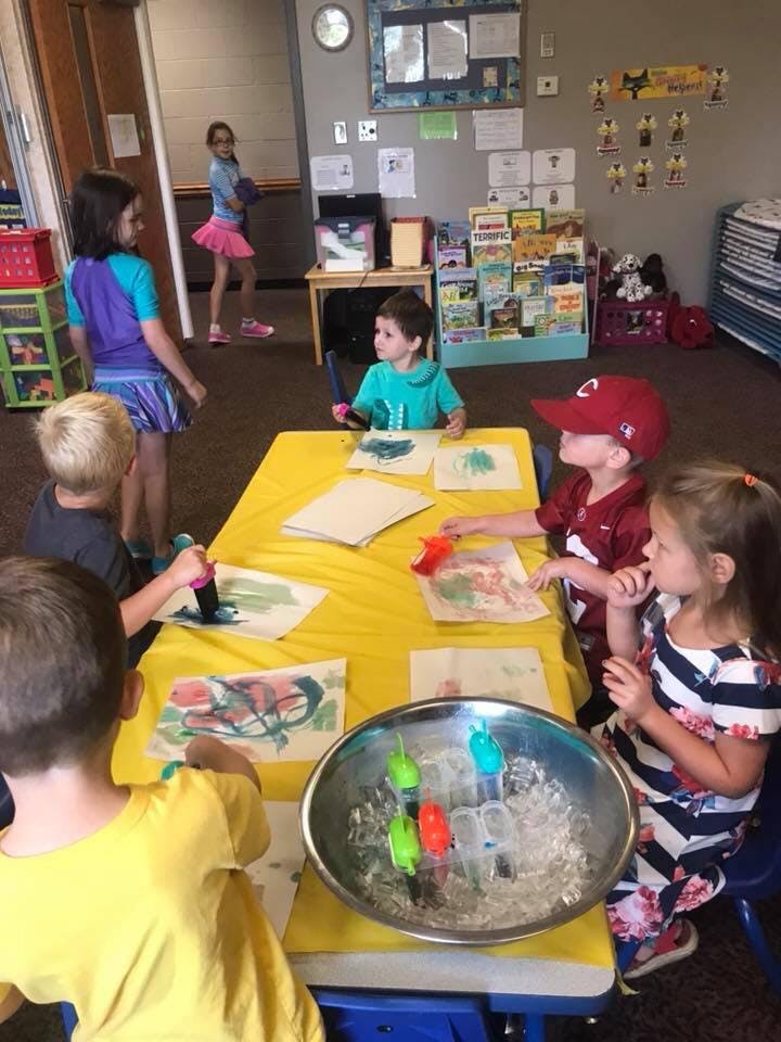 Children painting at a table in a classroom