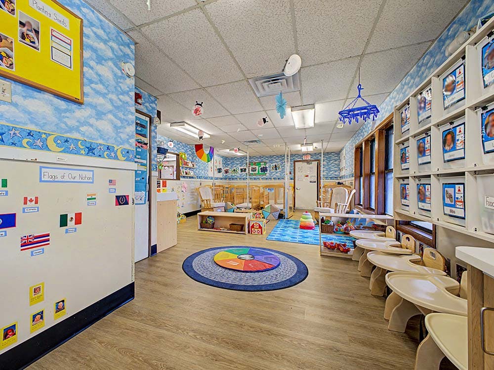 Colorful playroom with small tables, flags, and cribs