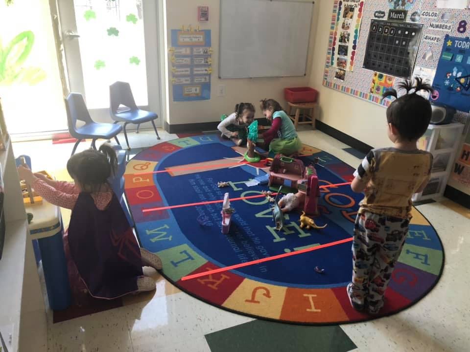 Children playing on a rug in a classroom
