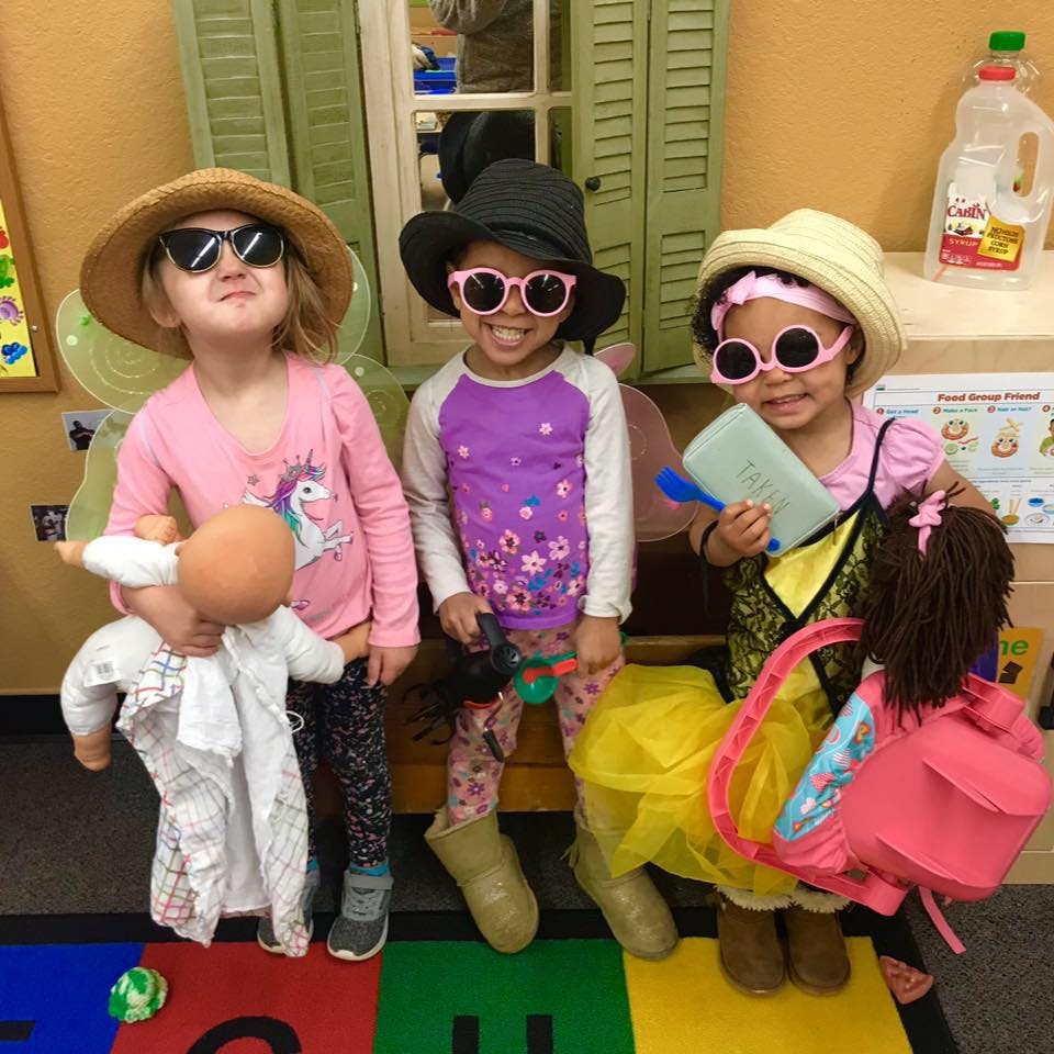 Three children in hats and sunglasses, one holding a doll