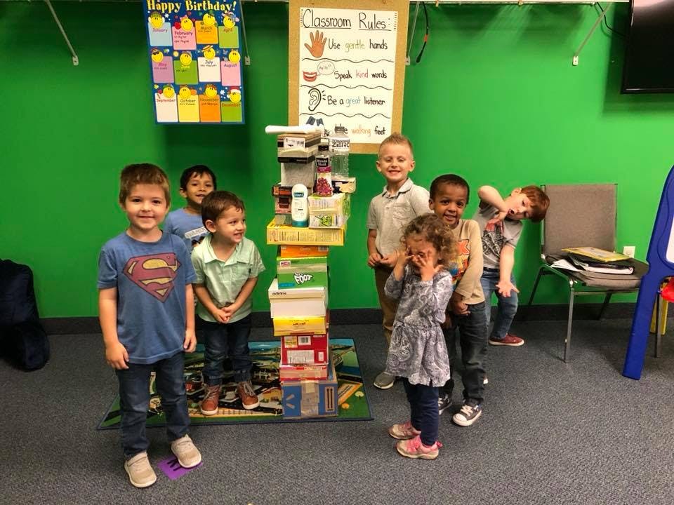 Children standing around a tall stack of boxes in a classroom