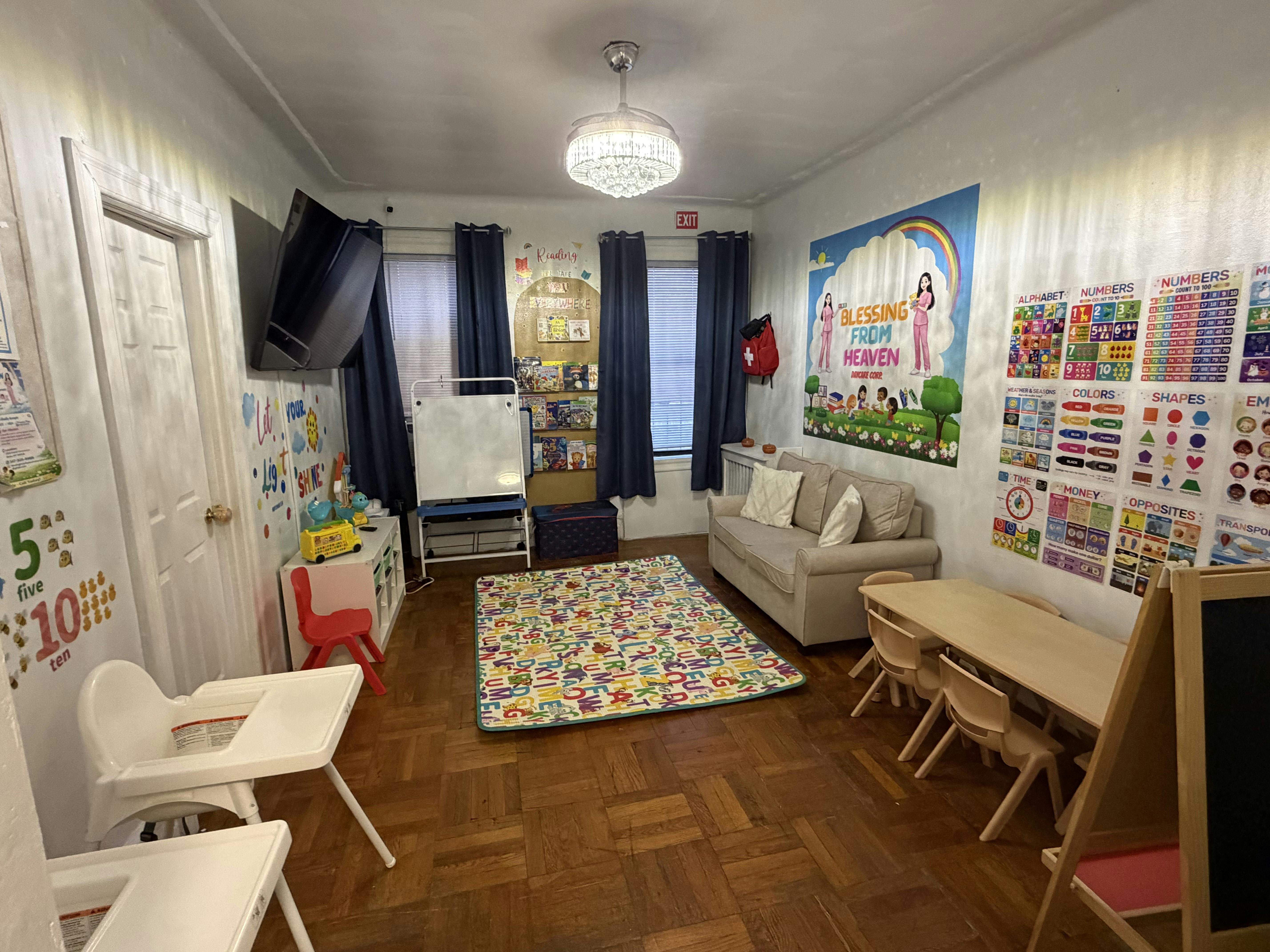 Daycare room with toddler furniture, an alphabet rug, and educational posters on the walls