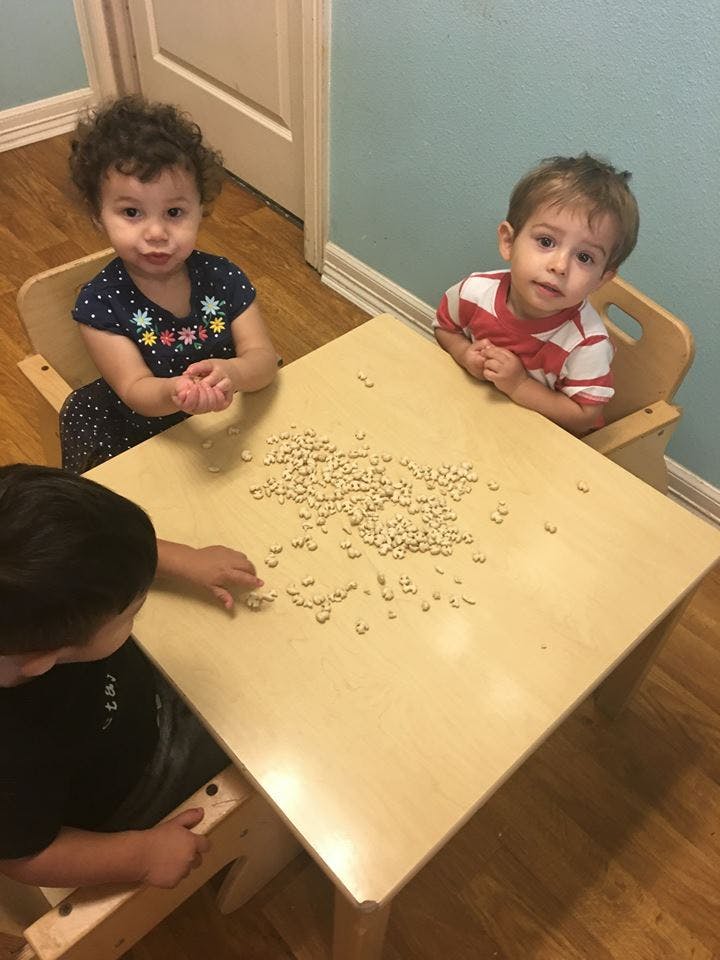 Three children at a table with small objects scattered objects