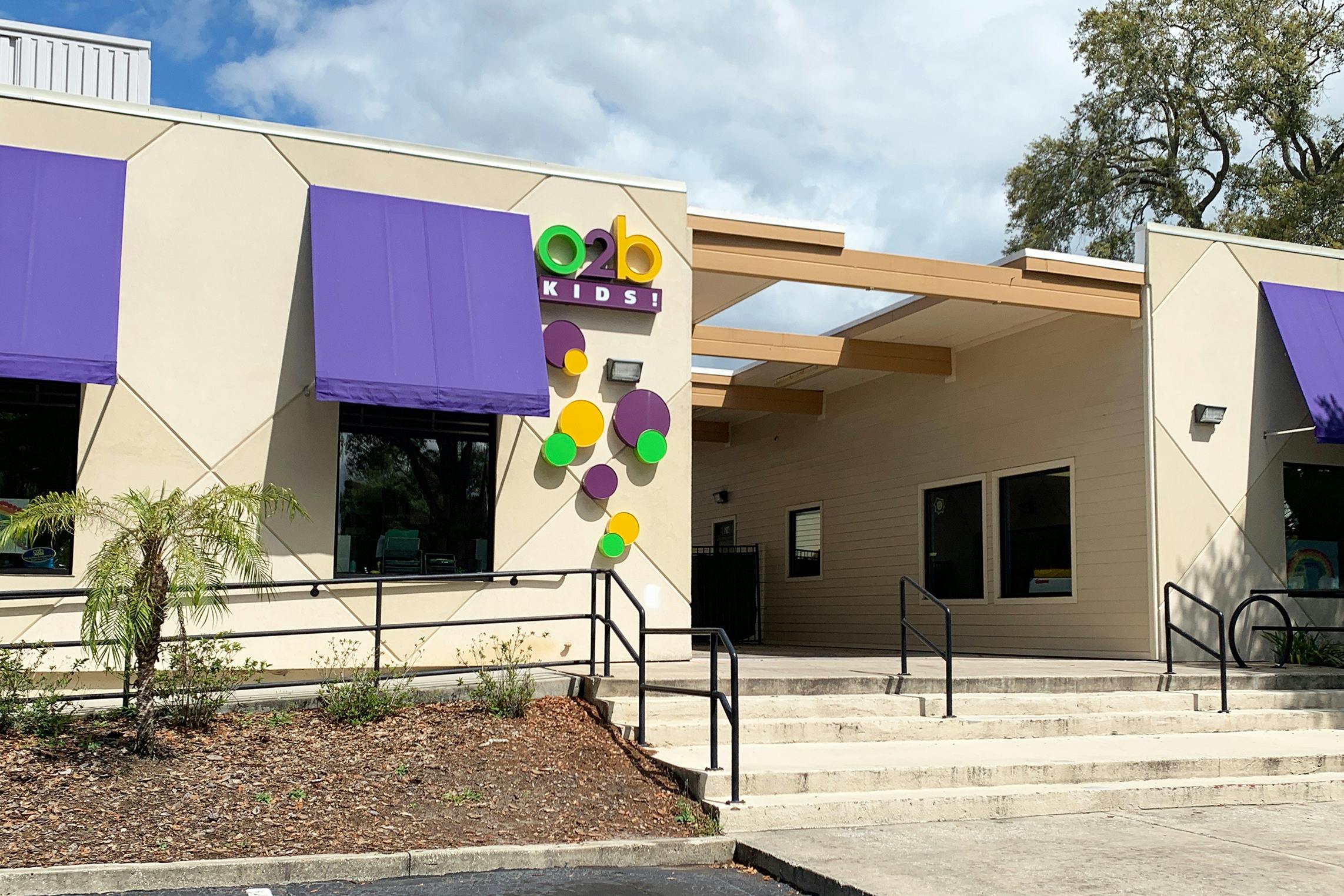 Exterior of O2b Kids building with purple awnings and sign
