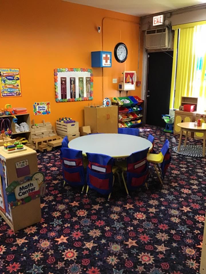 Classroom with small tables and chairs, colorful walls, and patterned carpet