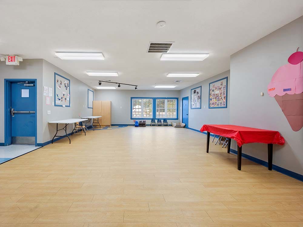 Empty children's playroom with tables and a large ice cream cone decoration