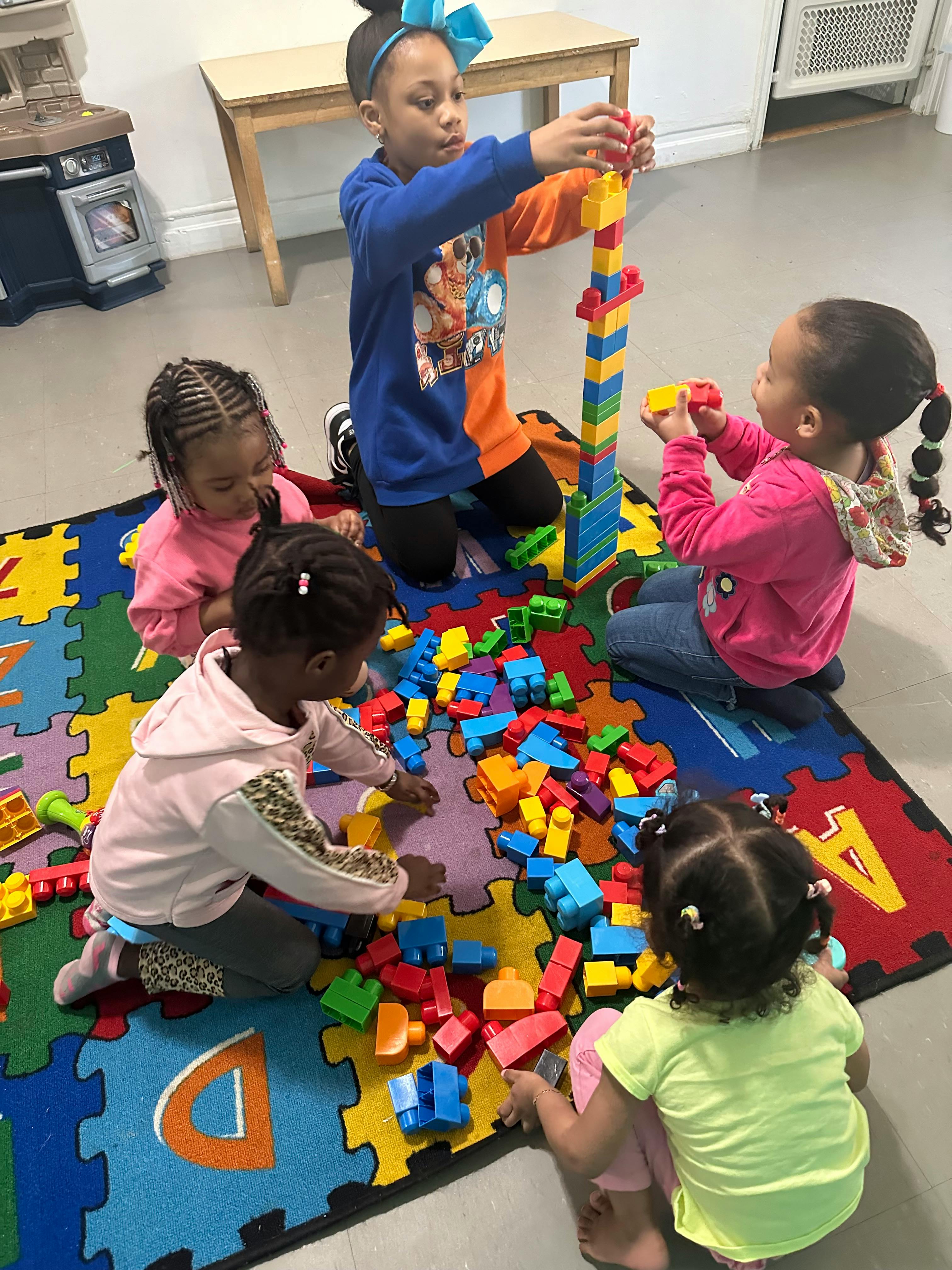 Four children playing with colorful building blocks on a puzzle mat