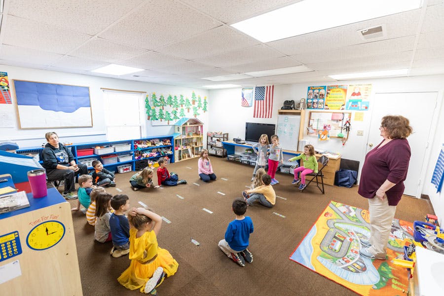 Adults and children sitting on the floor in a classroom