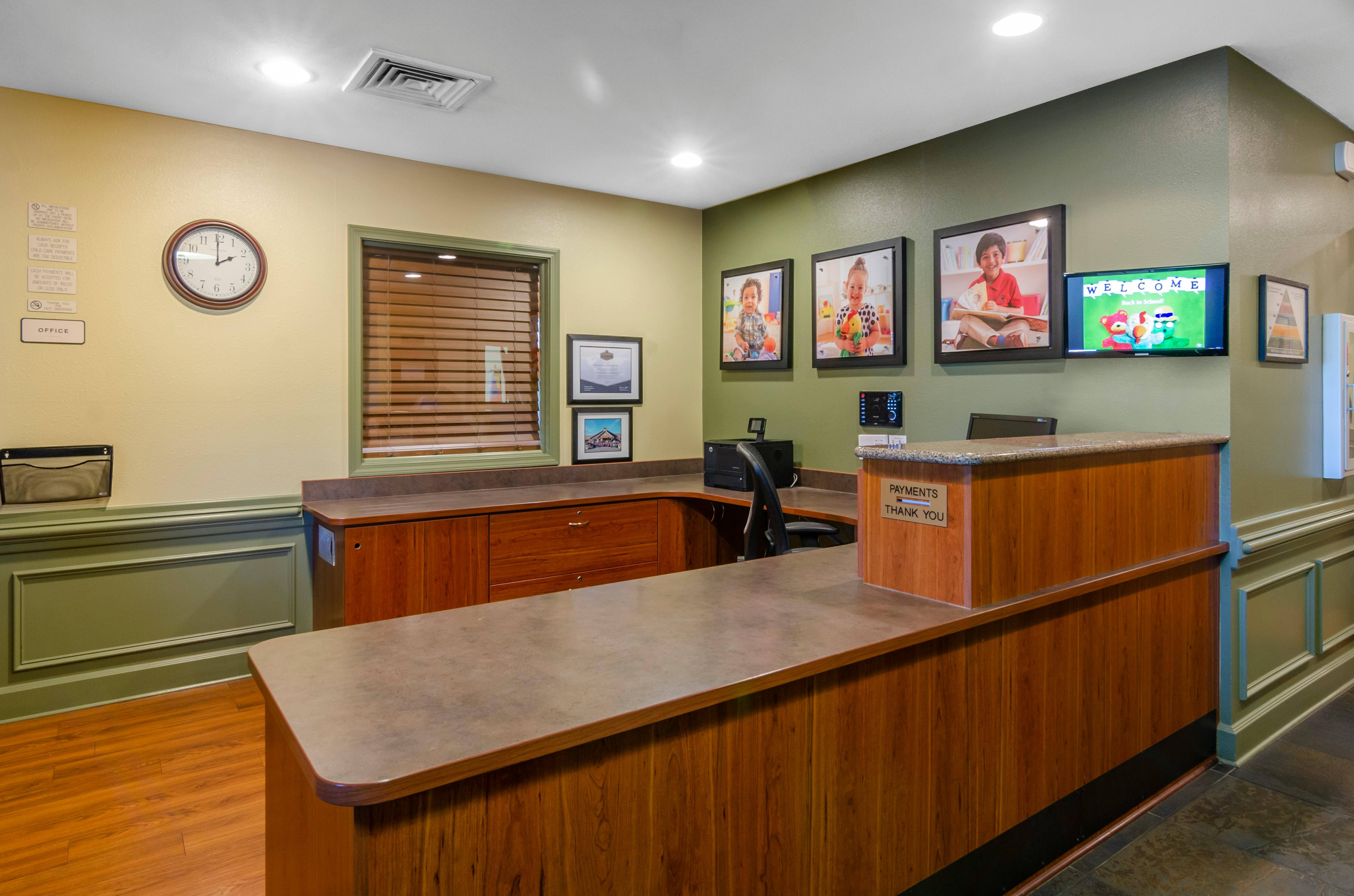 Reception desk with child photos on the wall and a 'Welcome' screen