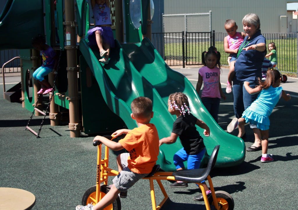 Children playing on a playground slide and riding a tricycle