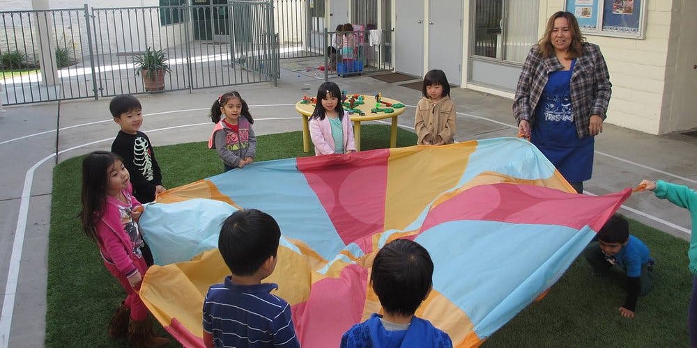 Adult and children playing with a colorful parachute
