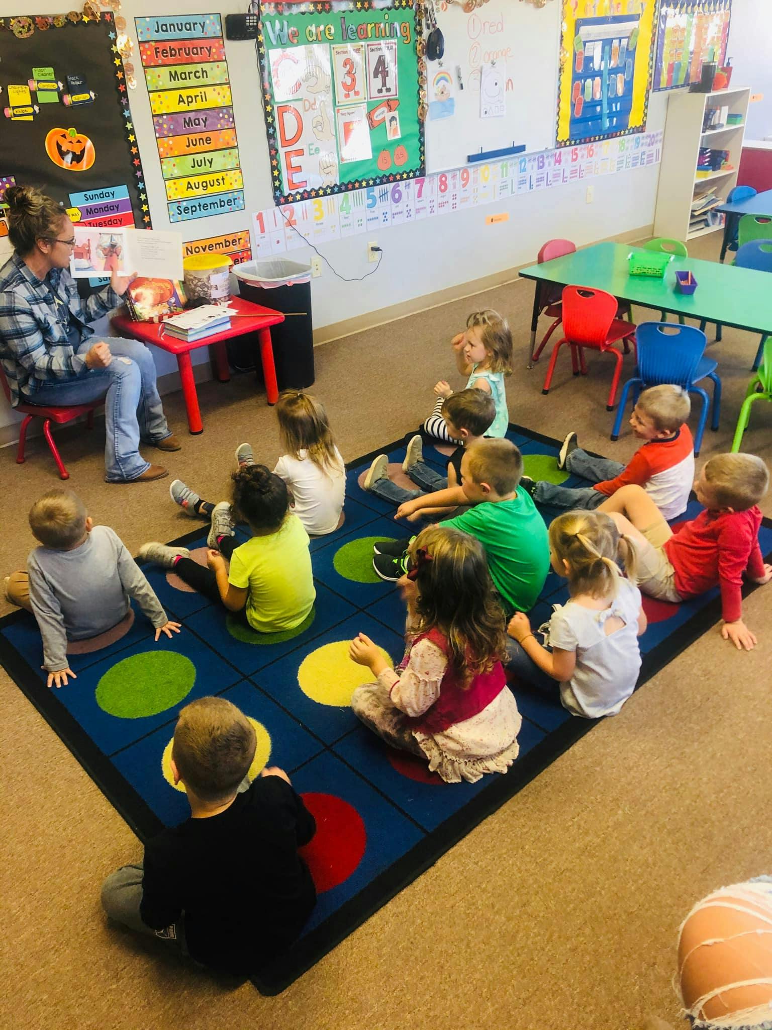 Adult reading to children sitting on a rug in a classroom