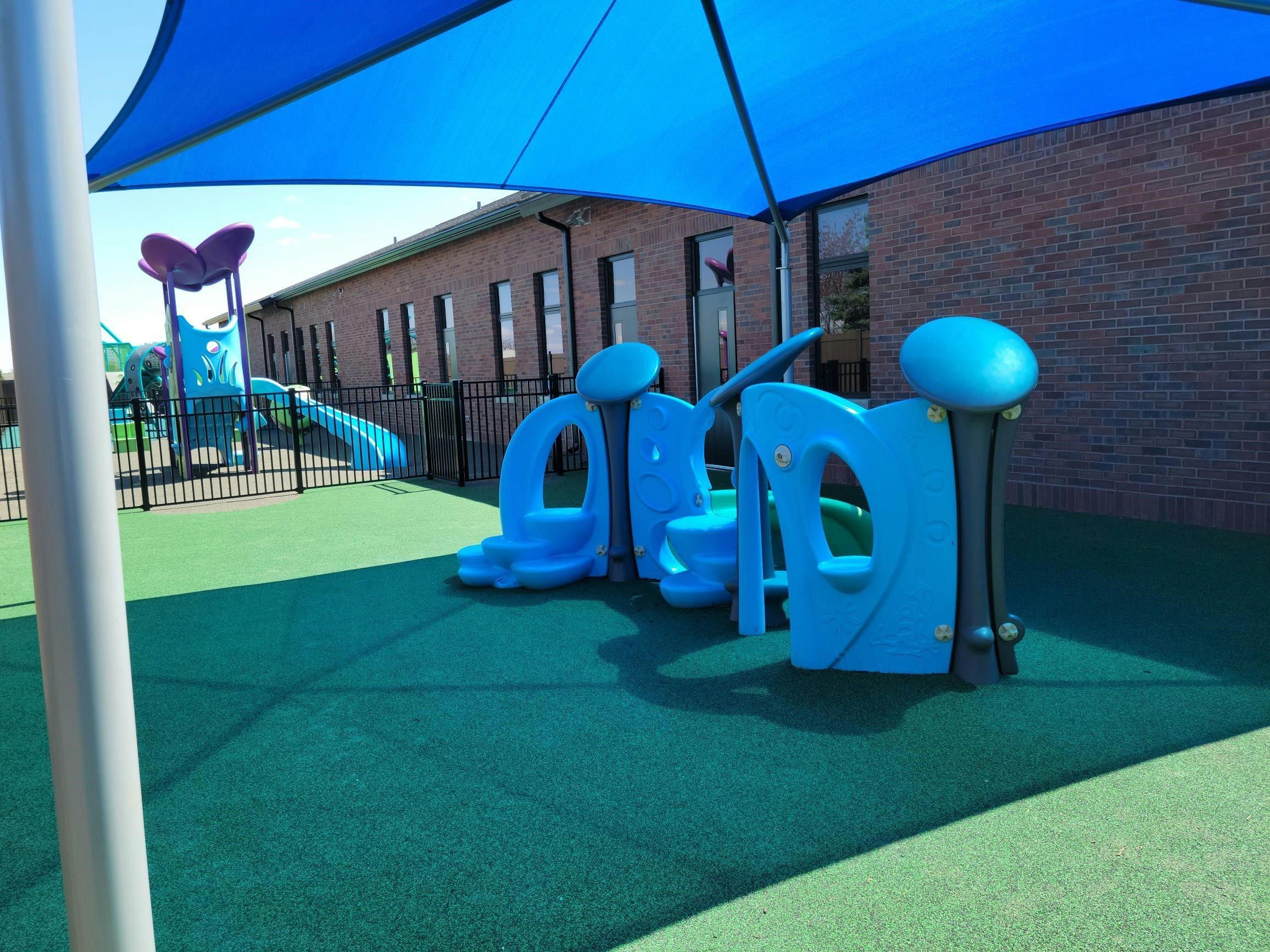 Playground with blue play structures and a blue shade canopy