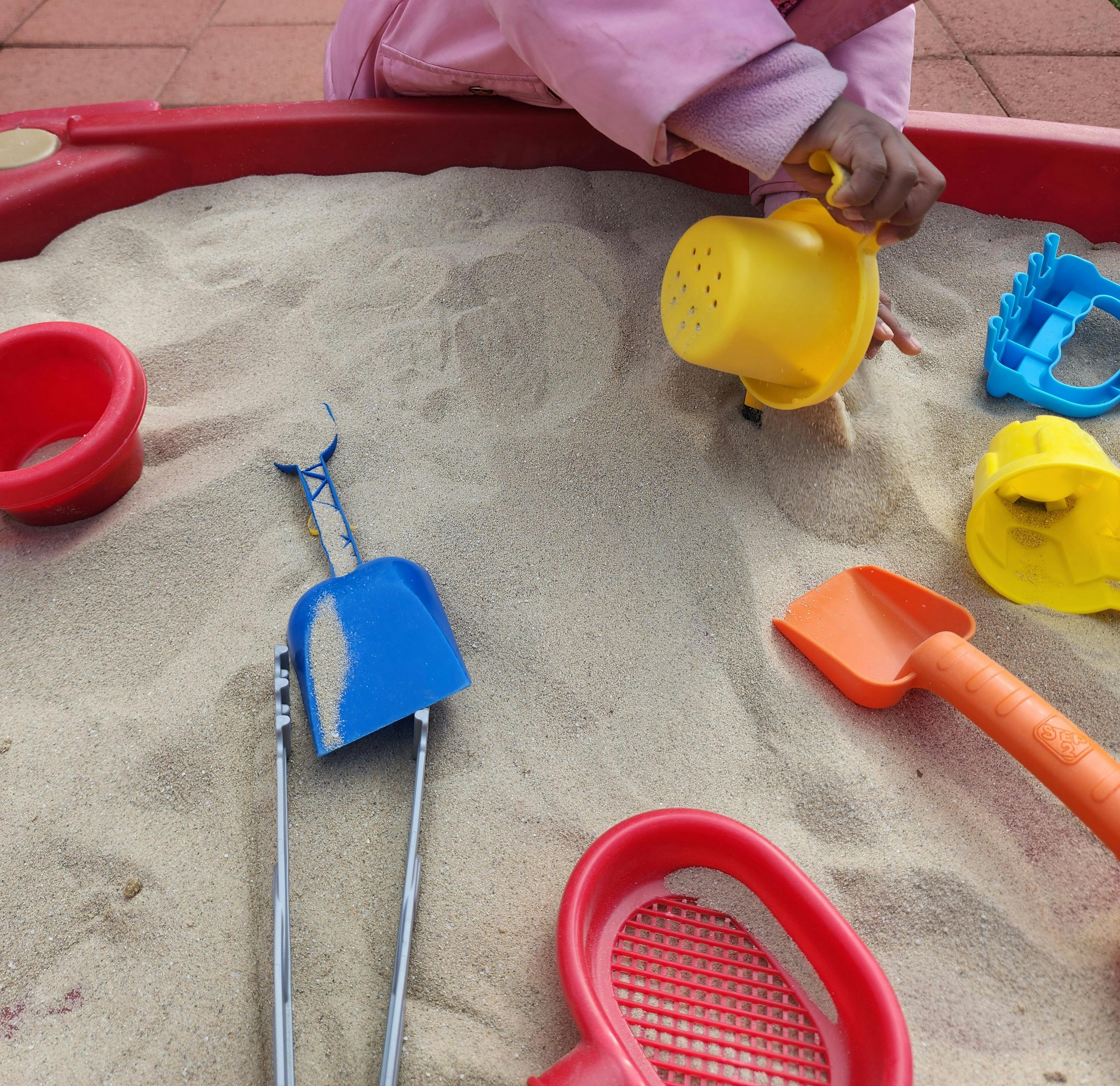 Child playing in a sandbox with sand toys