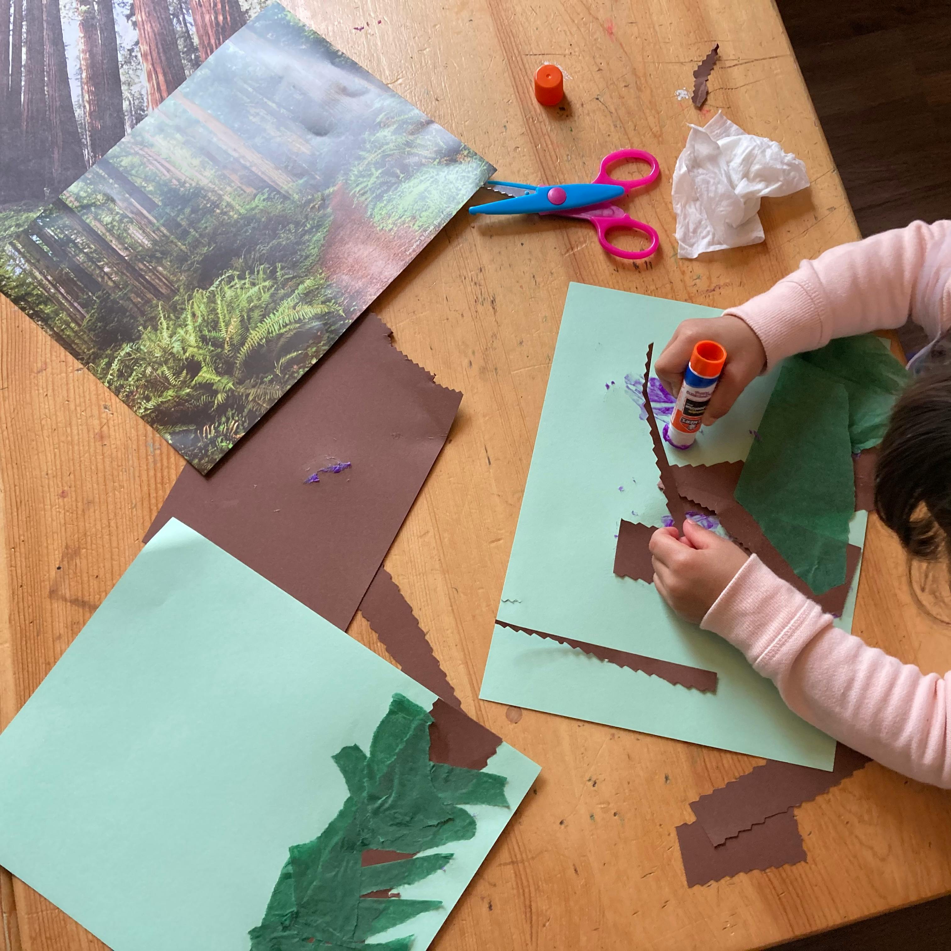 Child gluing paper onto a light green sheet