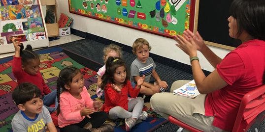 Adult and children sitting on a rug in a classroom