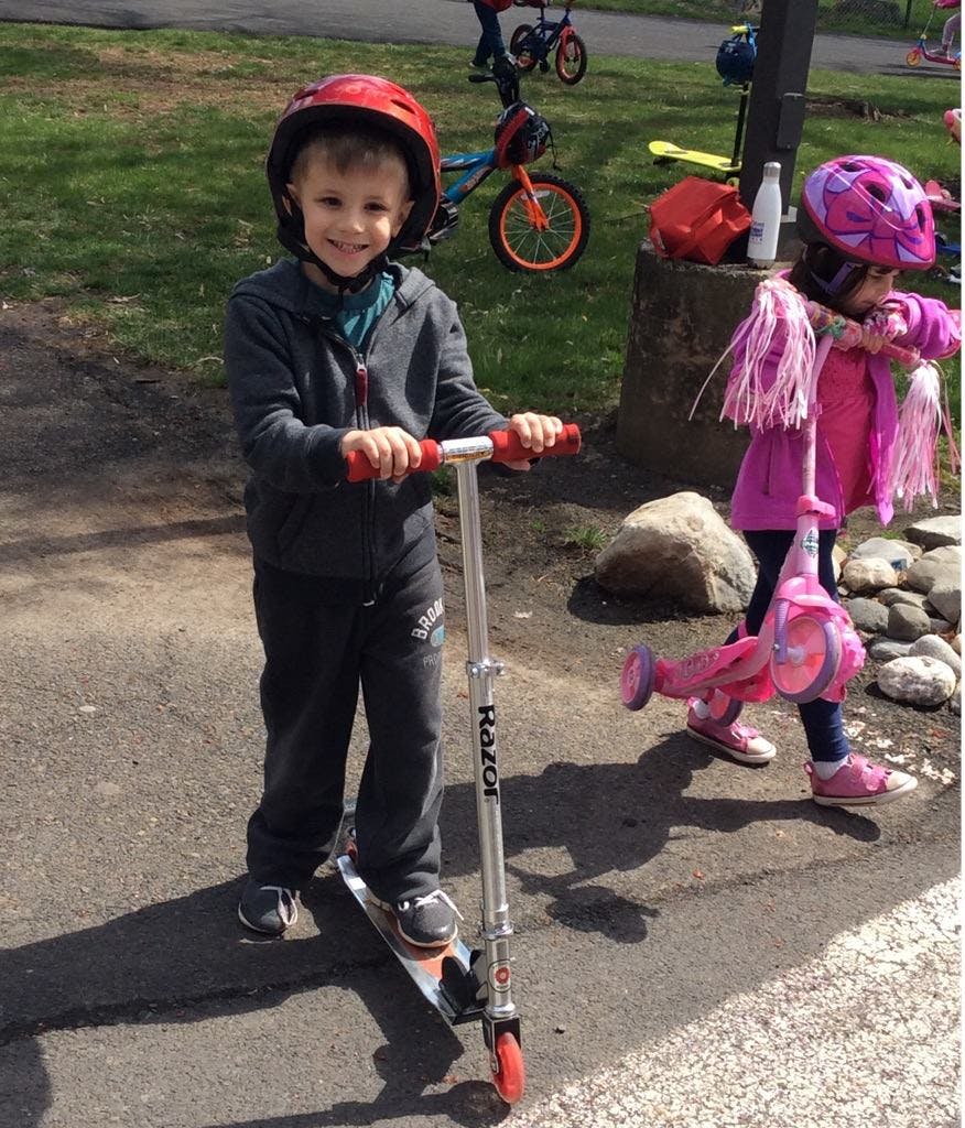 Child in a red helmet standing on a scooter