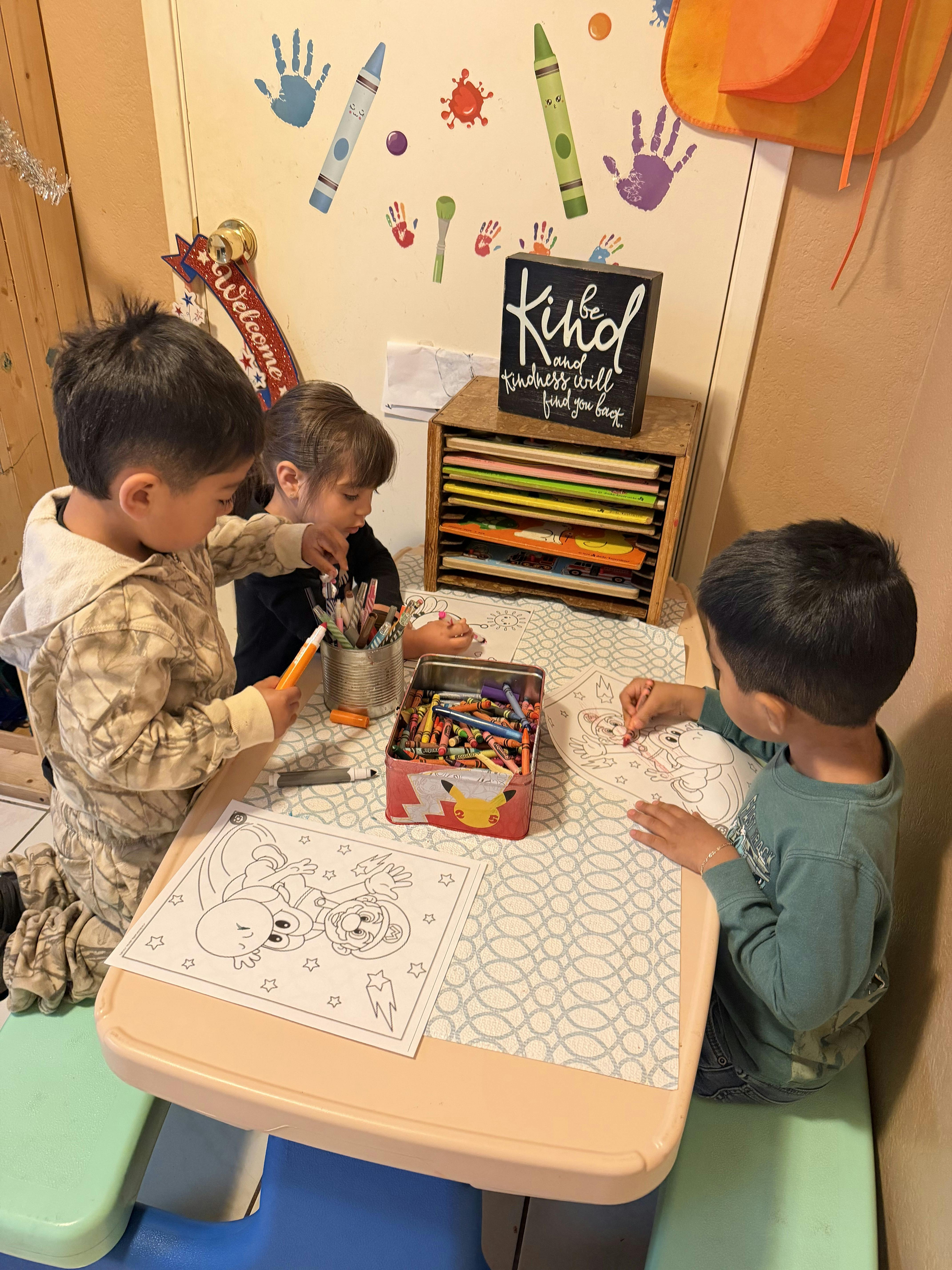 Three children drawing and coloring at a table with crayons and markers
