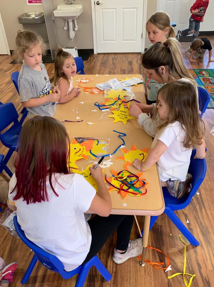 Children and an adult making crafts at a table