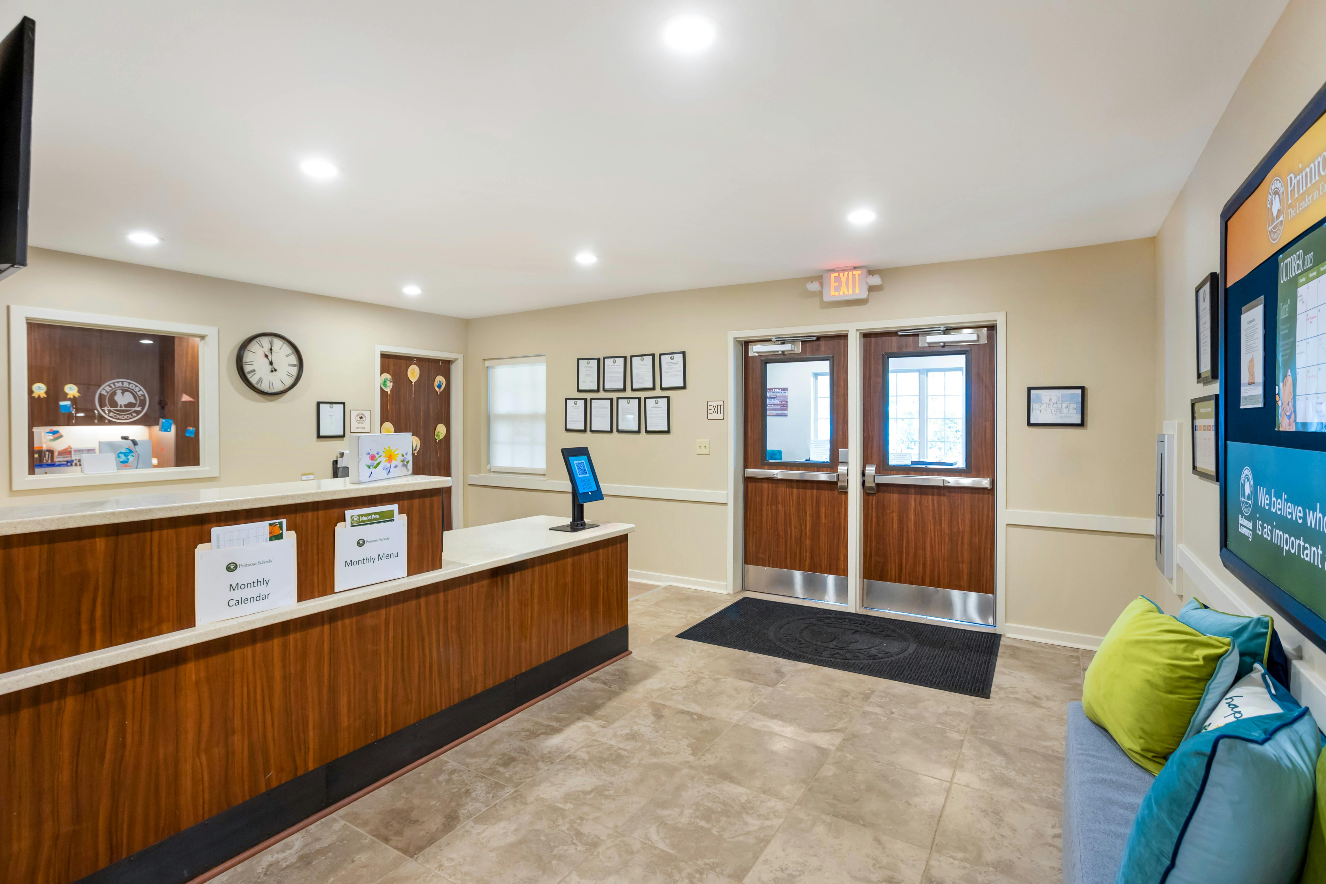 Reception desk with “Monthly Calendar” and “Monthly Menu” signs, exit doors