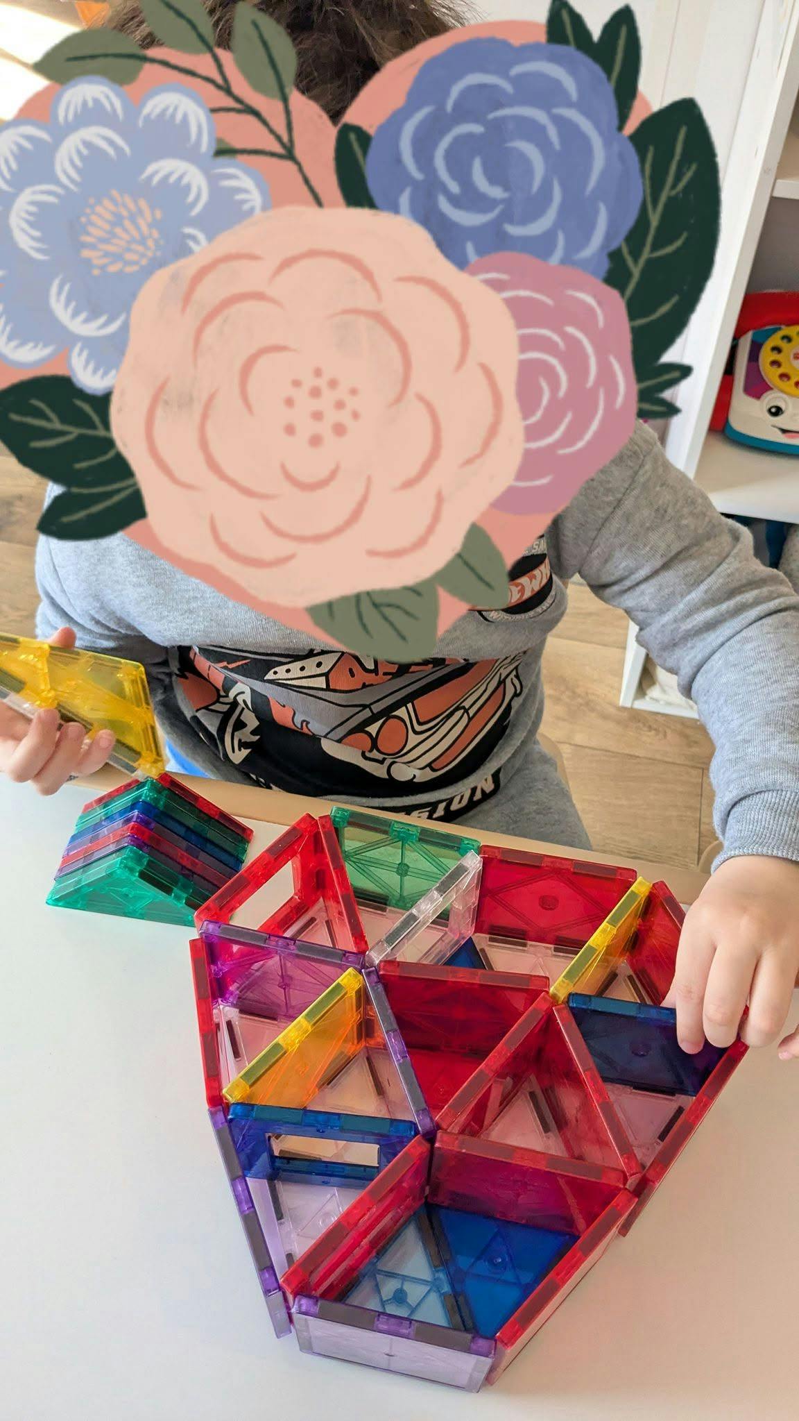 Child playing with colorful magnetic tiles at a table
