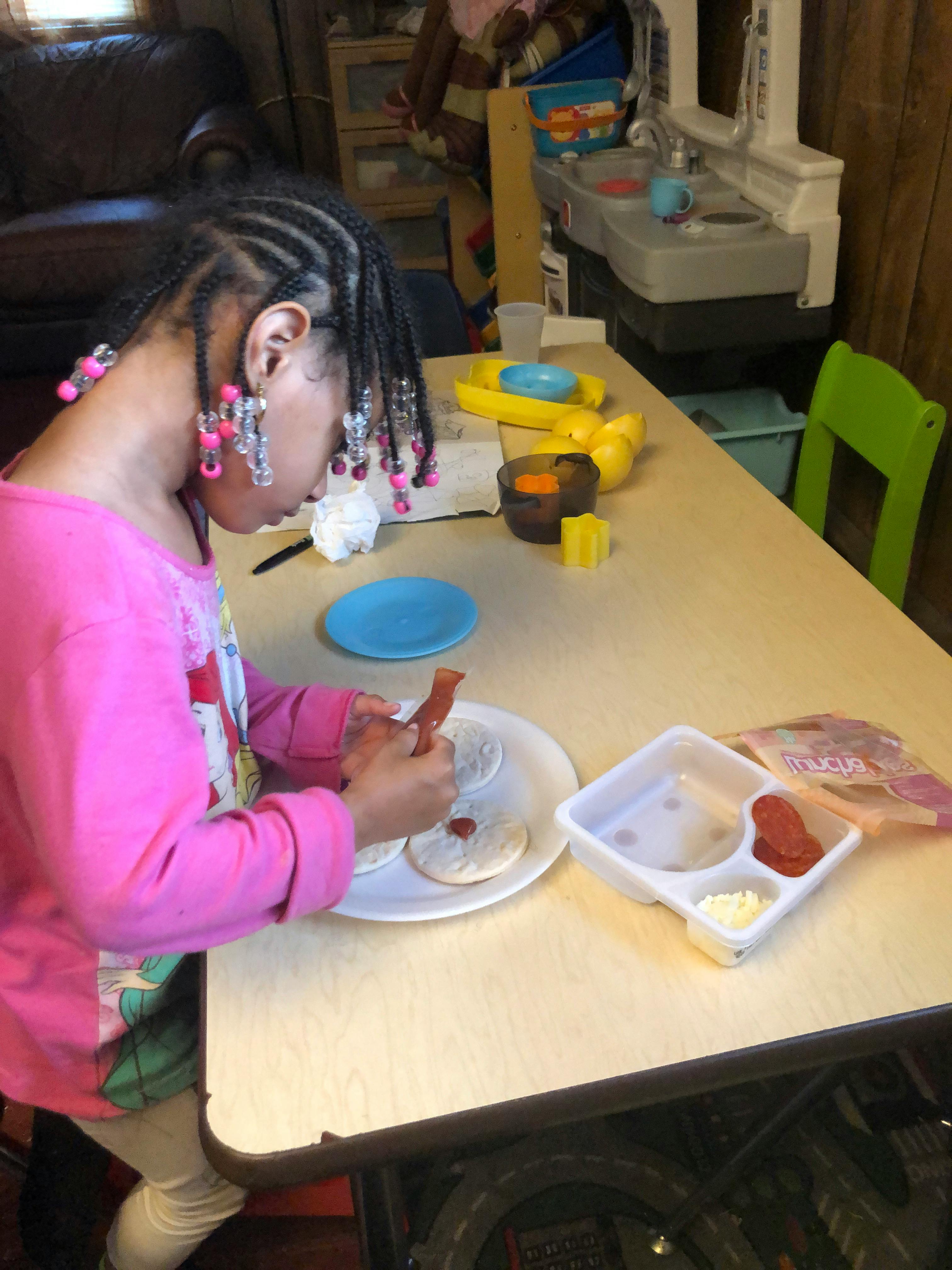 Child making a mini pizza at a table