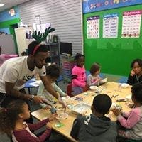 Adult helping children at a table in a classroom