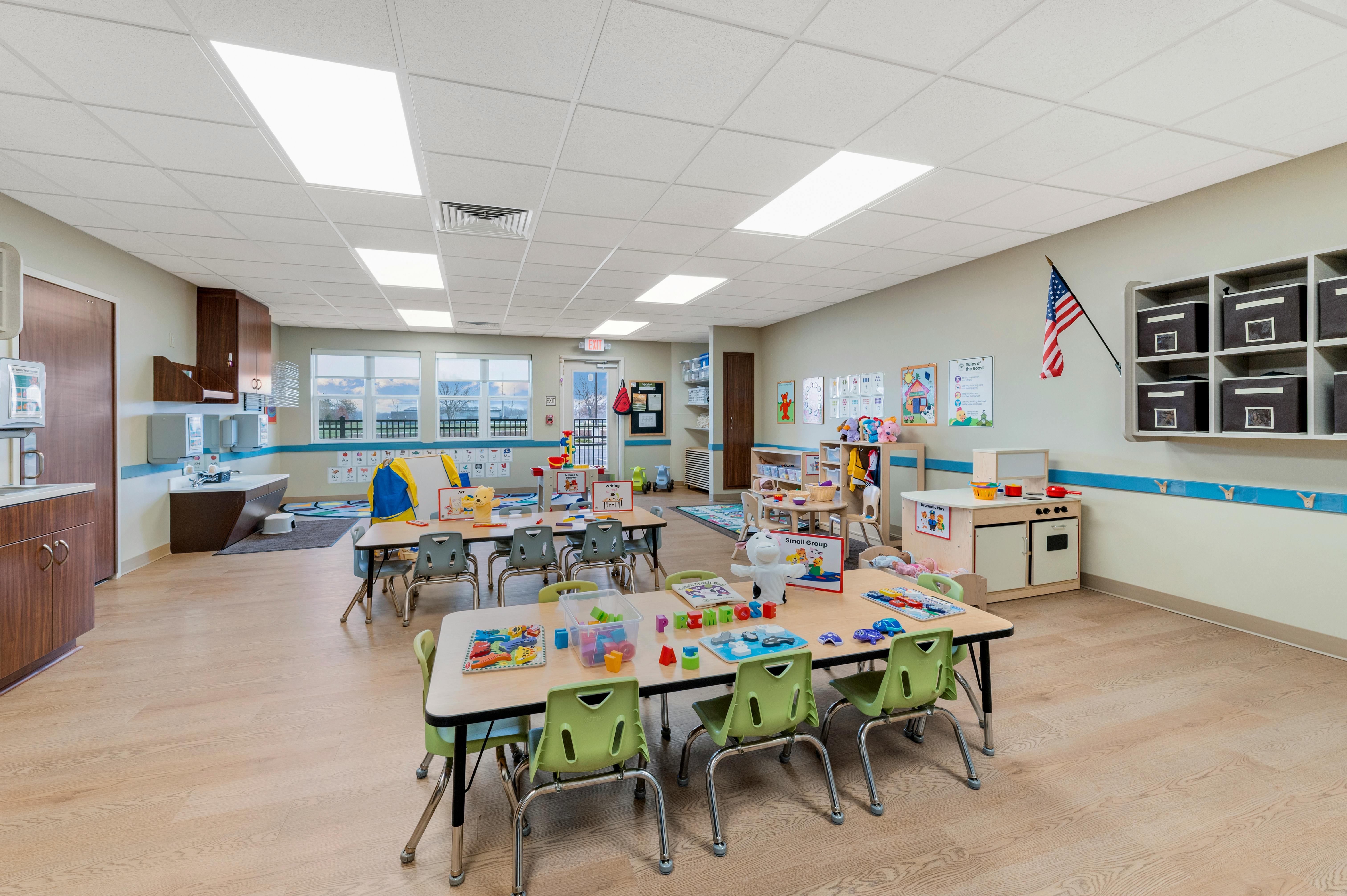 Classroom with child-sized tables and chairs, play kitchen, and sinks