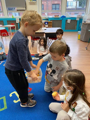 Children playing with small yellow objects in a classroom