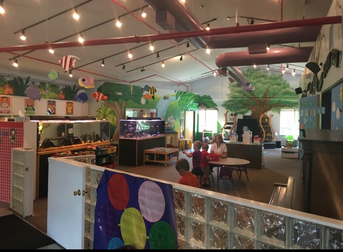People and children in a brightly lit indoor play area with fish decorations