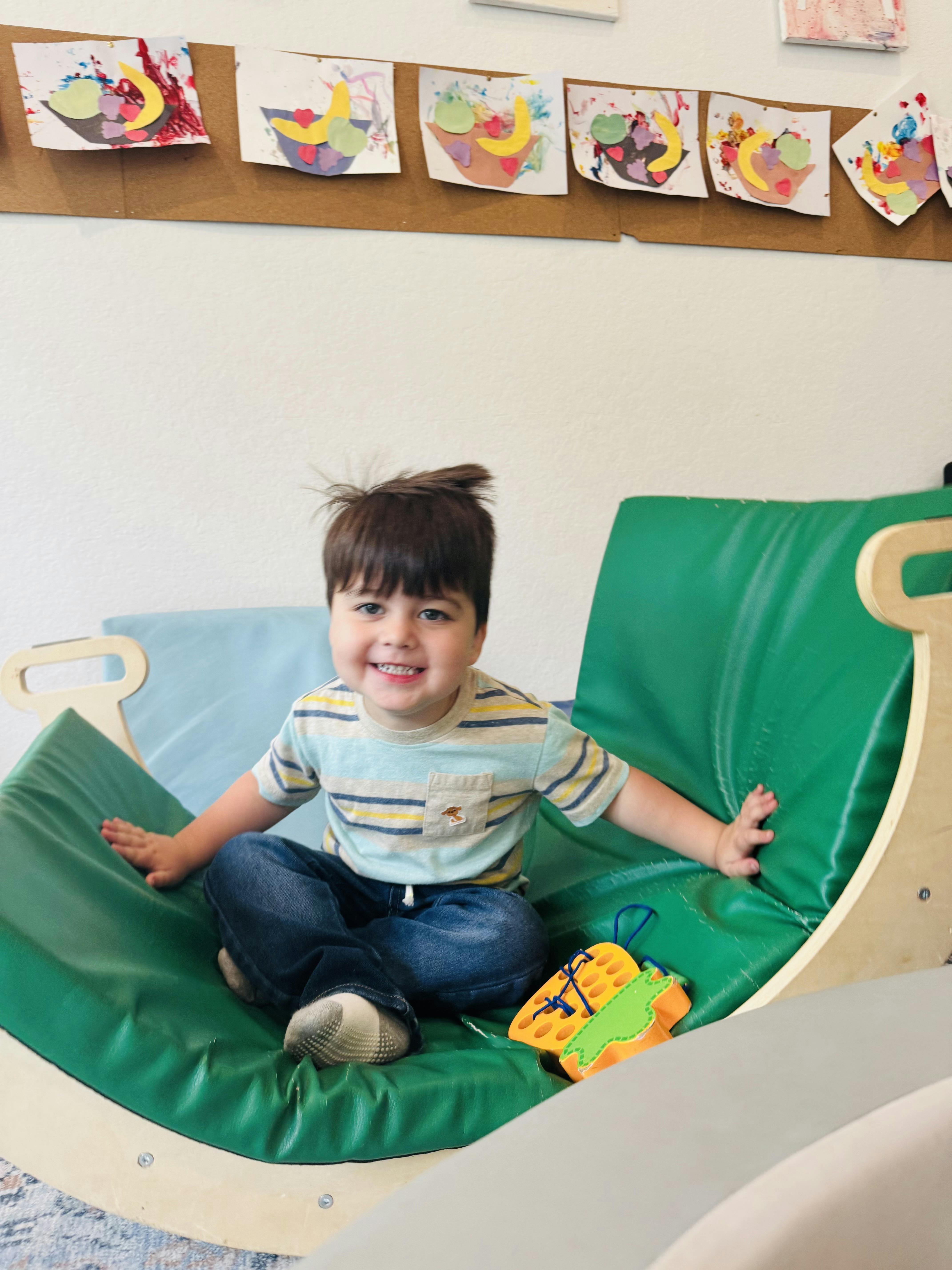 Child sitting in a green rocking chair