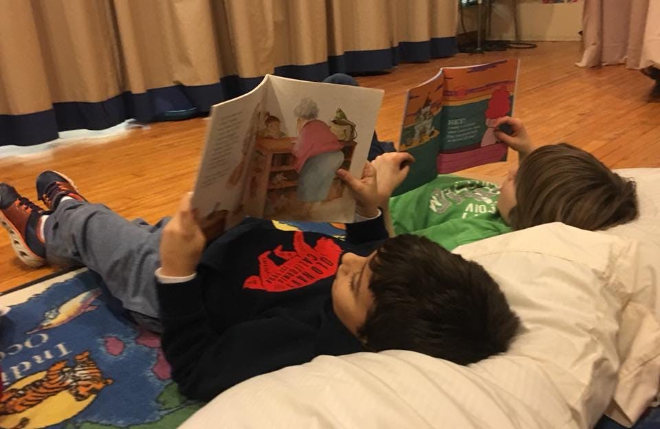 Two children lying down and reading books