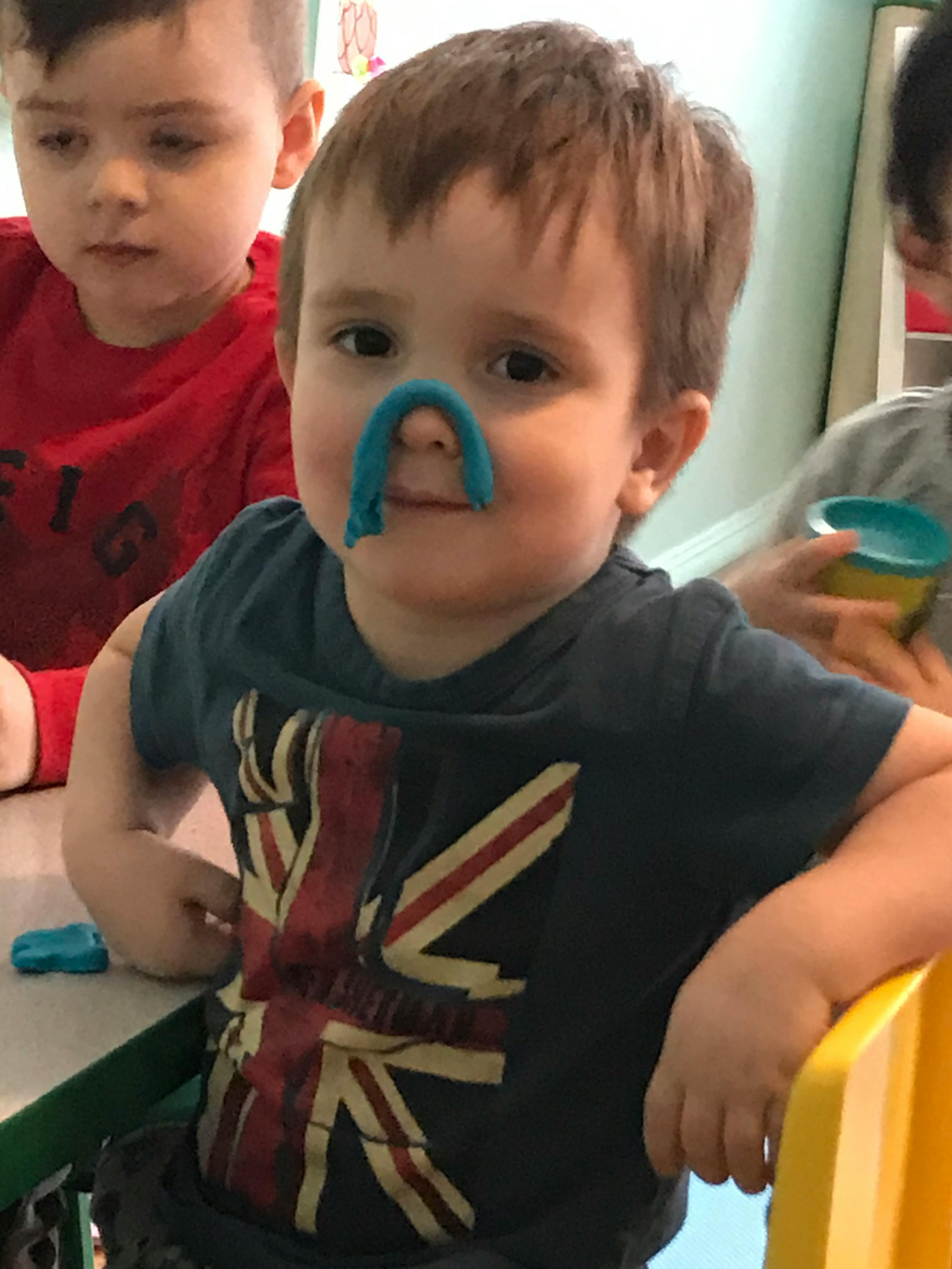 Child with blue playdough on their nose