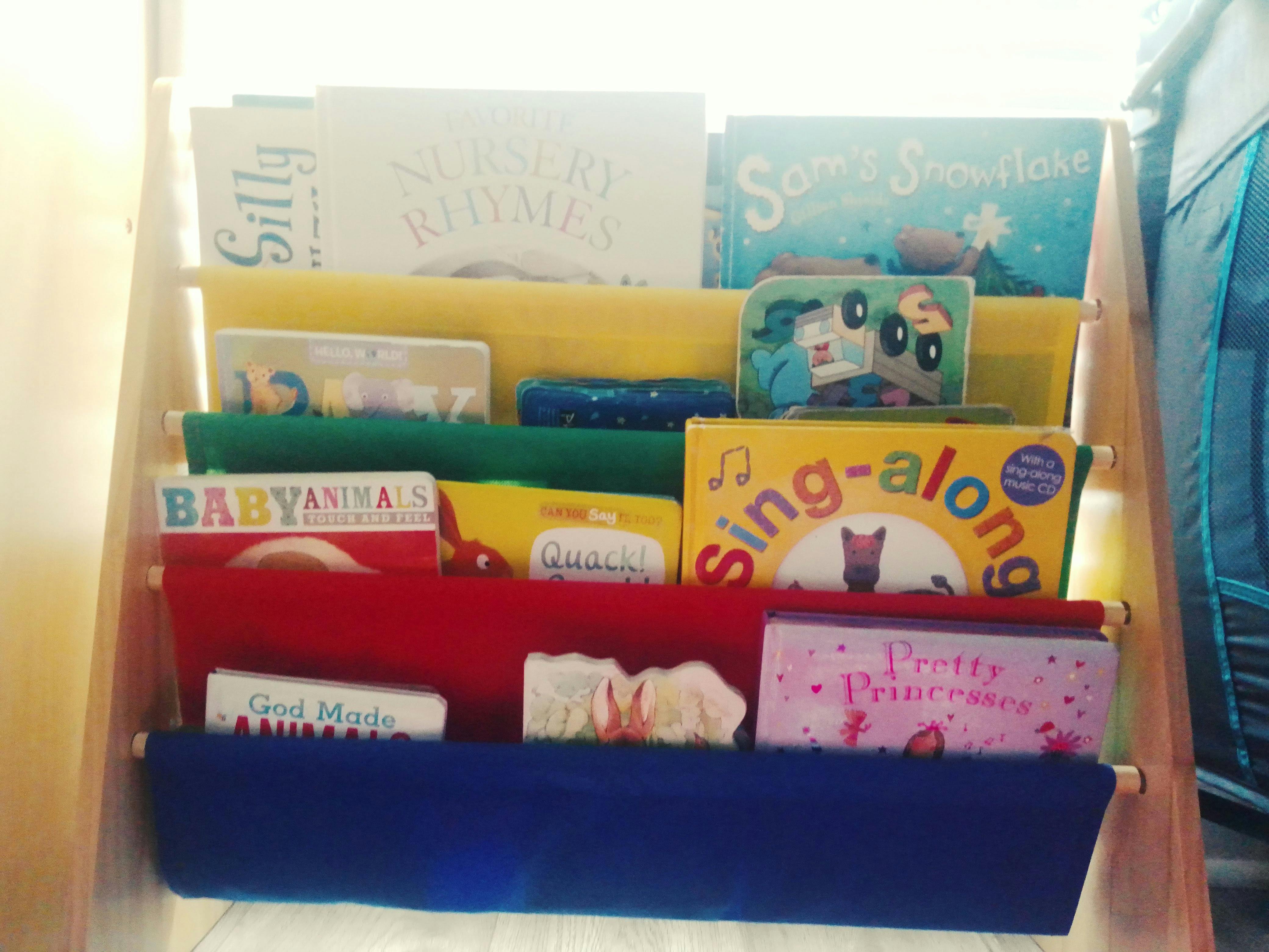 Children's books displayed on a colorful fabric sling bookshelf