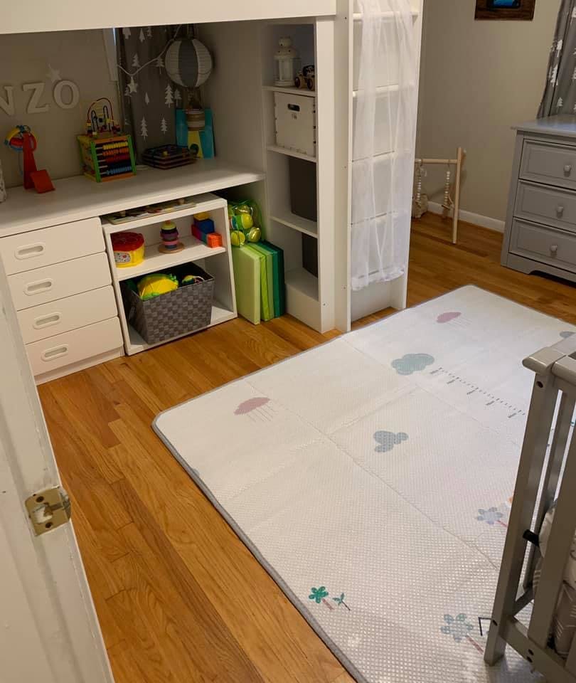 Child's room with a white desk, shelves with toys, and a play mat on the floor