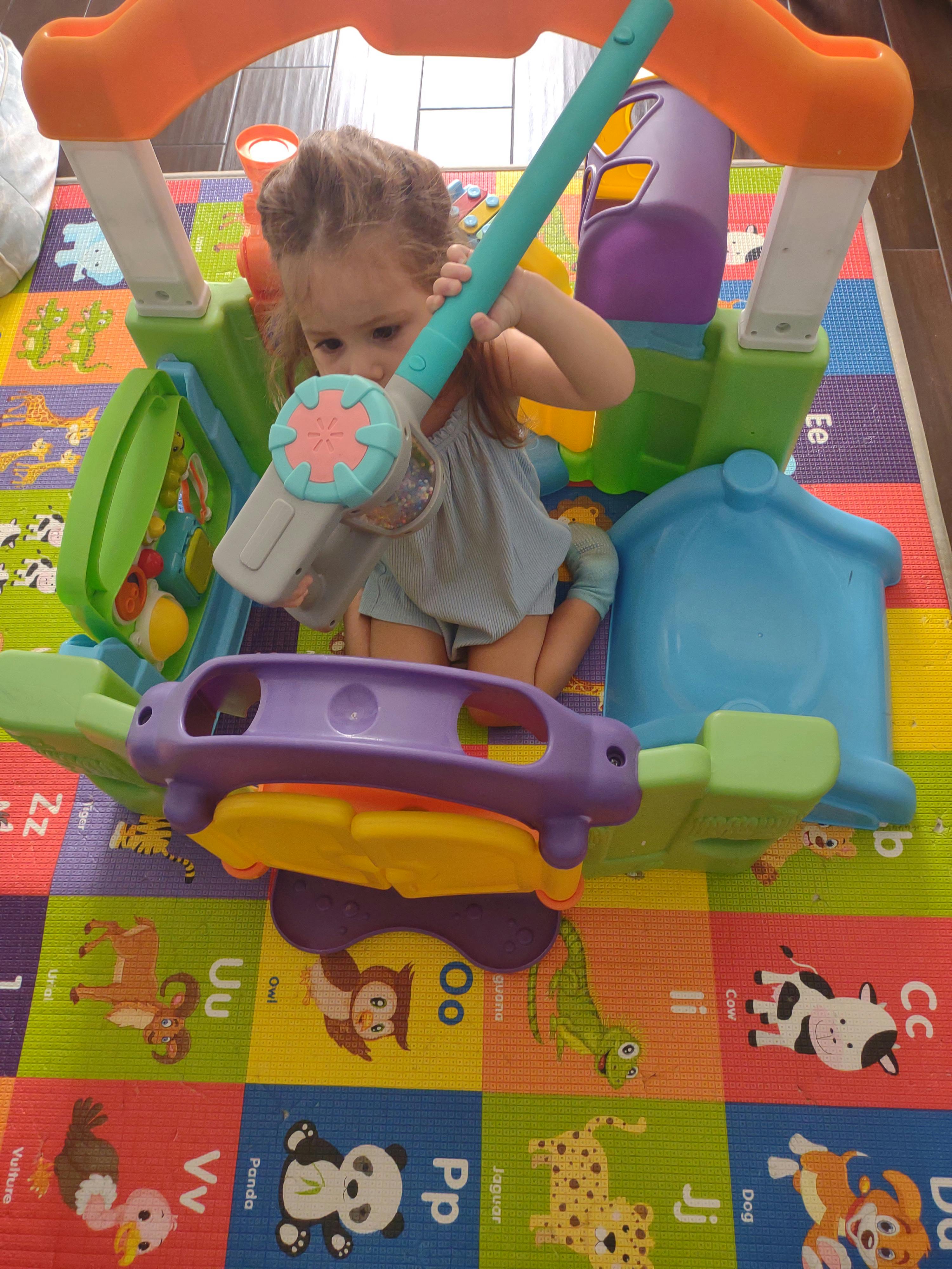 Child playing with a toy hammer and colorful play structure