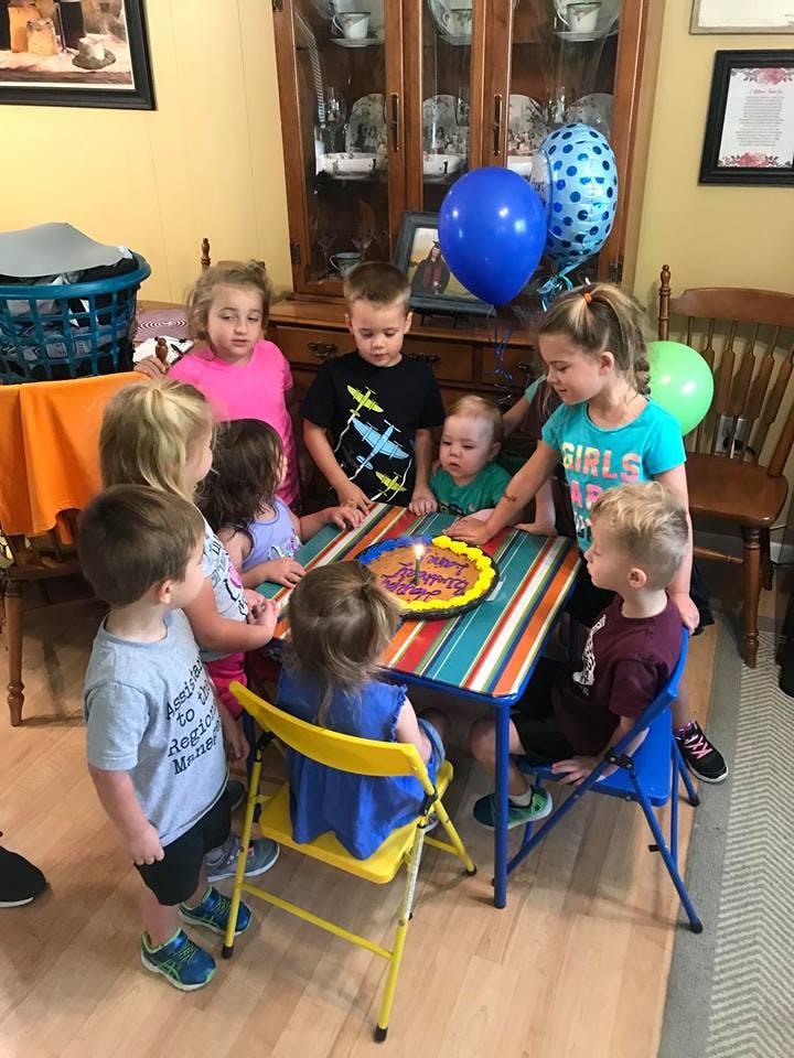 Group of children gathered around a table with a birthday cake