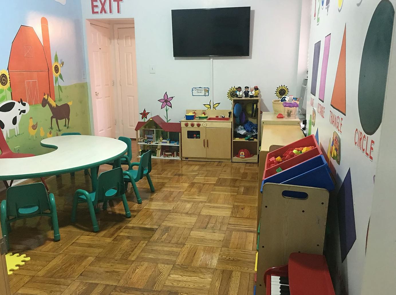 Children's classroom with small tables and chairs, toys, and wall decorations