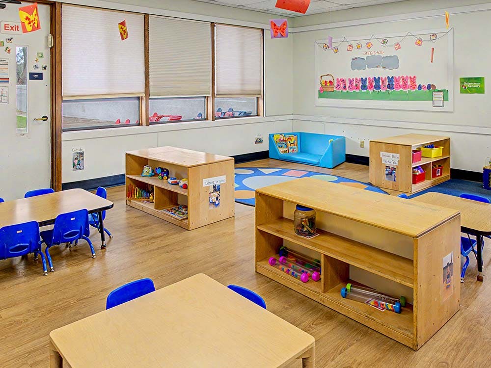 children's classroom with small tables, chairs, and toy shelves