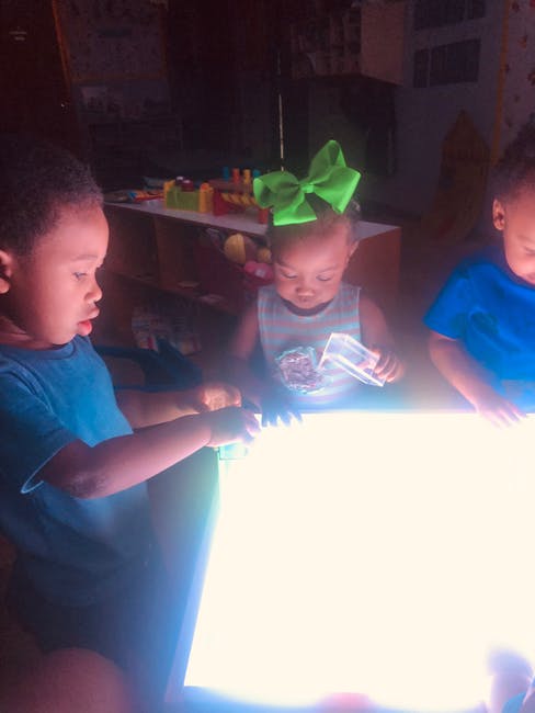 Three children playing with a light table