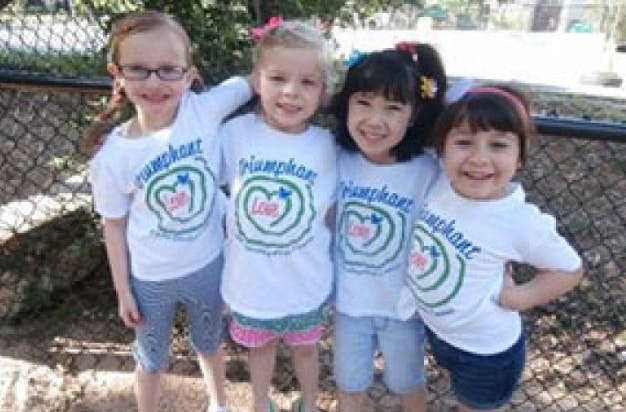 Four children in matching white shirts with a heart logo