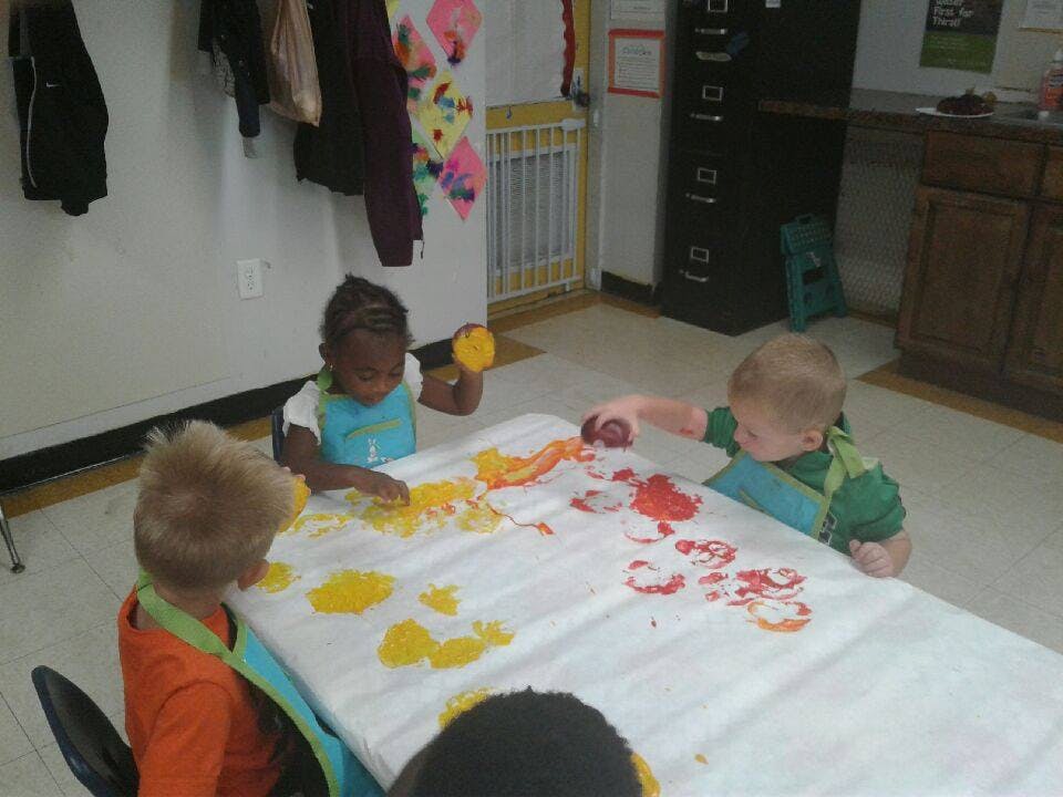 Children finger painting at a table
